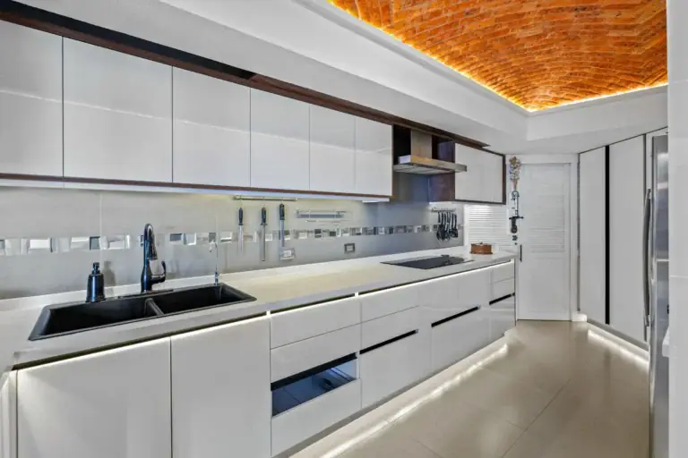 Casa del Foro, kitchen with white handleless cabinets, a double sink and under-cabinet lighting beneath a brick vaulted ceiling, San Miguel de Allende
