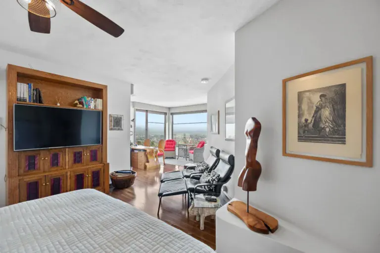 Casa del Foro, bedroom with a wood-framed television unit, a lounge area and a view through a wide opening, San Miguel de Allende