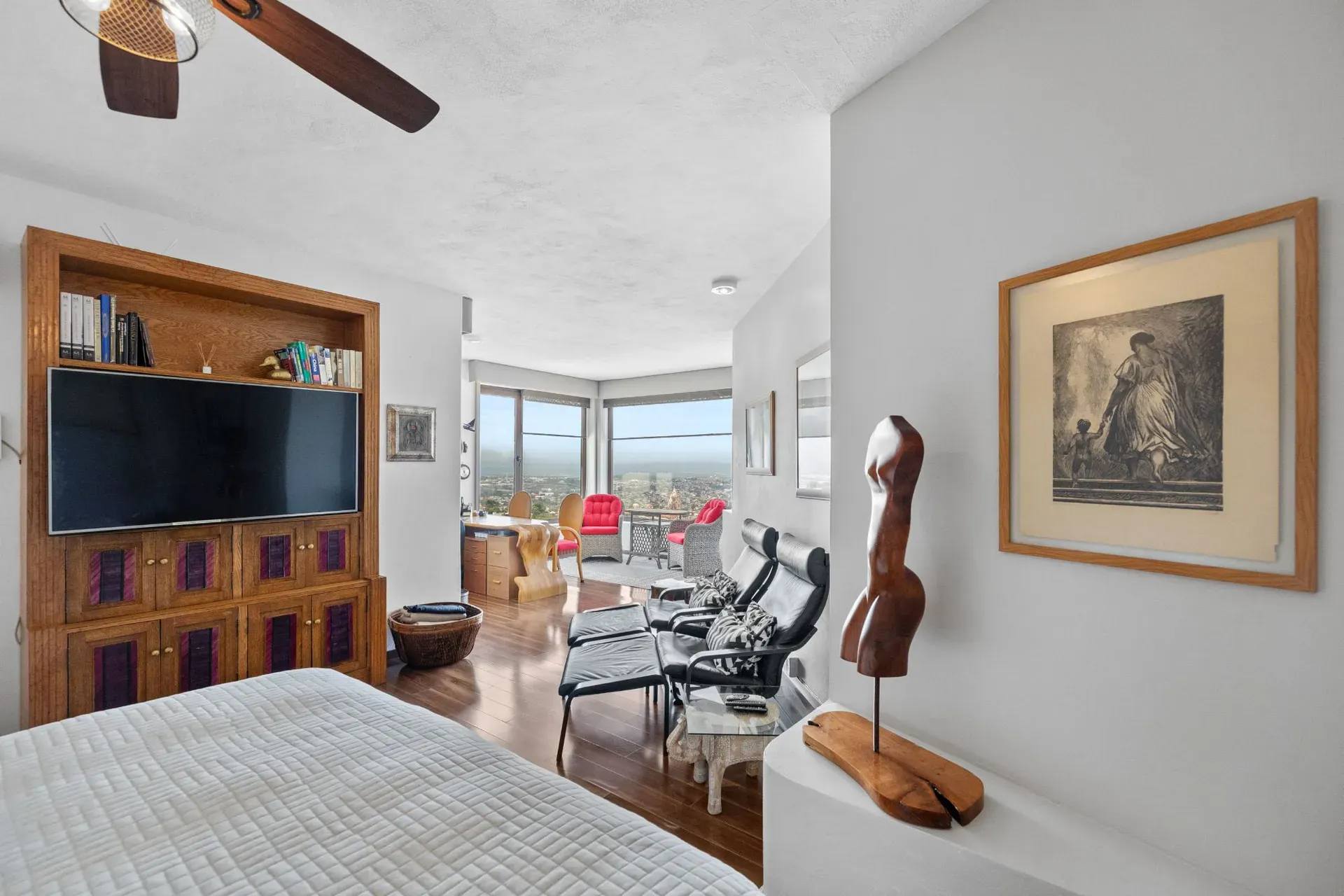 Casa del Foro, bedroom with a wood-framed television unit, a lounge area and a view through a wide opening, San Miguel de Allende