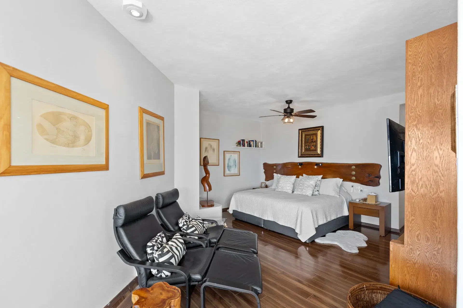 Casa del Foro, bedroom with a live-edge wood headboard, black leather lounge chairs and a ceiling fan, San Miguel de Allende