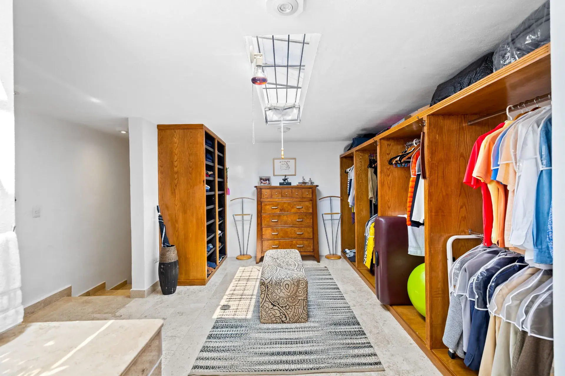 Casa del Foro, dressing room with open wood wardrobes, a dresser and a skylight, San Miguel de Allende