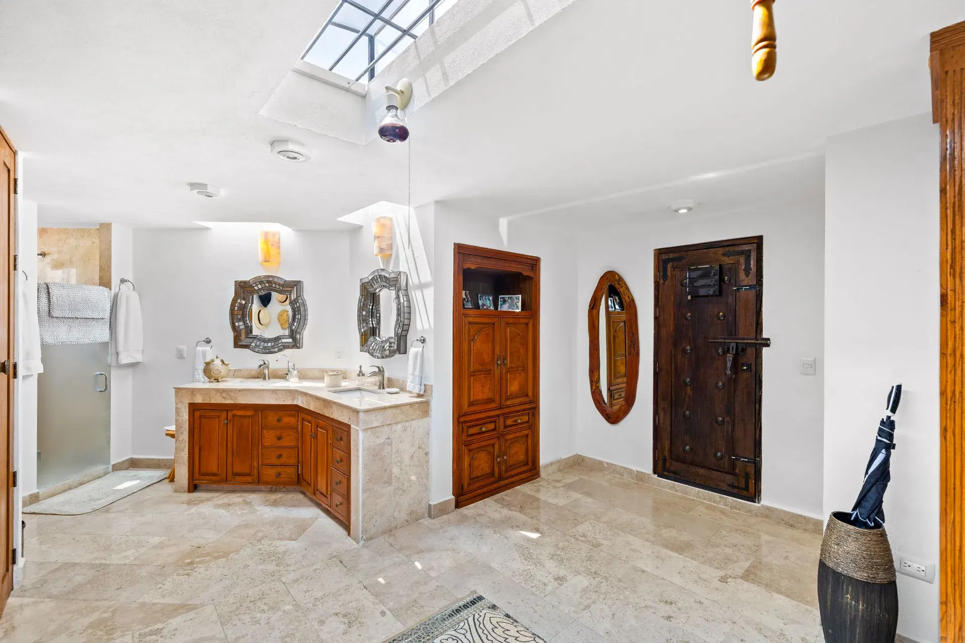 Casa del Foro, bathroom with a corner vanity, carved wood doors, a skylight and a glass shower, San Miguel de Allende