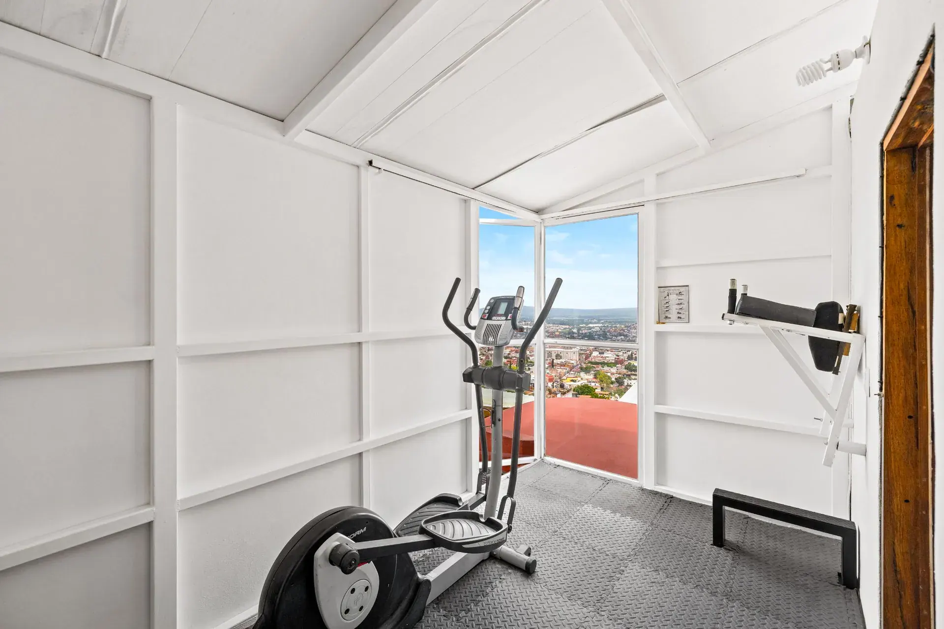 Casa del Foro, gym room with an elliptical trainer, a corner window with a view and a wall bar, San Miguel de Allende