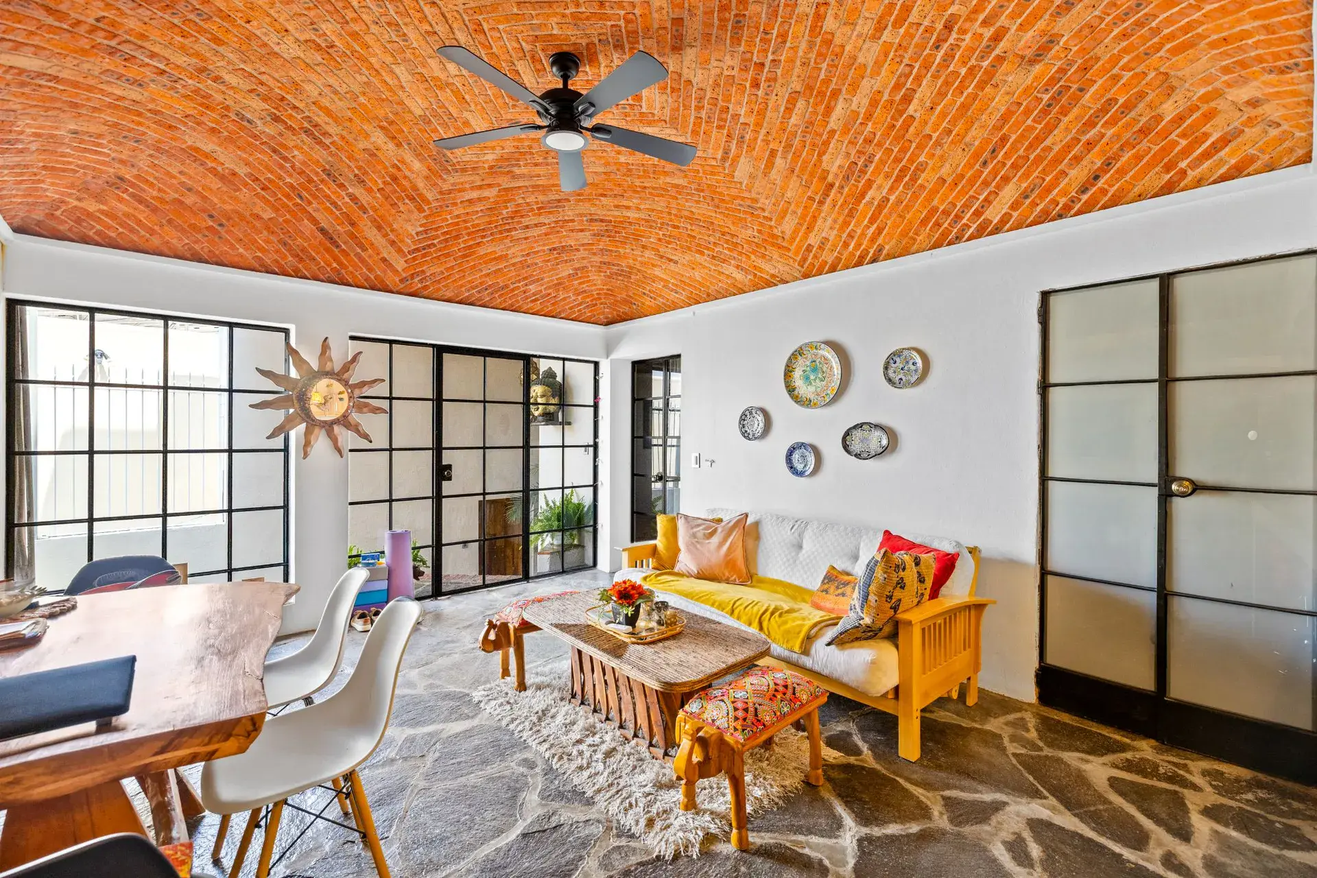 Casa del Foro, guest suite living area with a yellow futon, a wood table and steel-framed glass doors, San Miguel de Allende