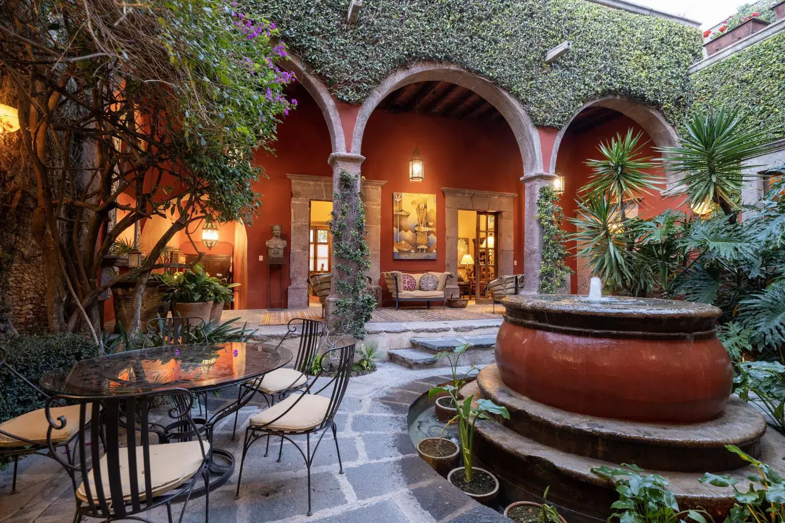 Casa Diana, arcaded courtyard with a terracotta fountain and an outdoor dining set, San Miguel de Allende