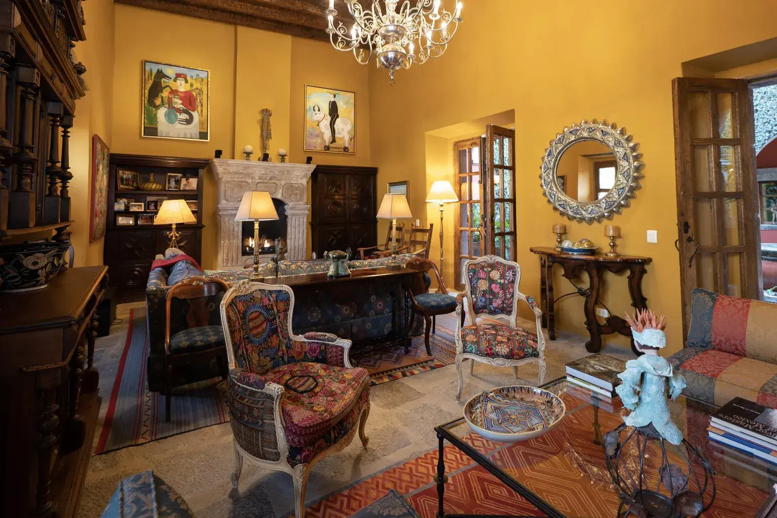 Casa Diana, sitting room with a stone fireplace, antique chairs and a crystal chandelier, San Miguel de Allende