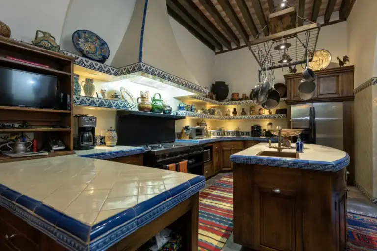 Casa Diana, kitchen with a tiled island, hanging pots and a wood beam ceiling, San Miguel de Allende
