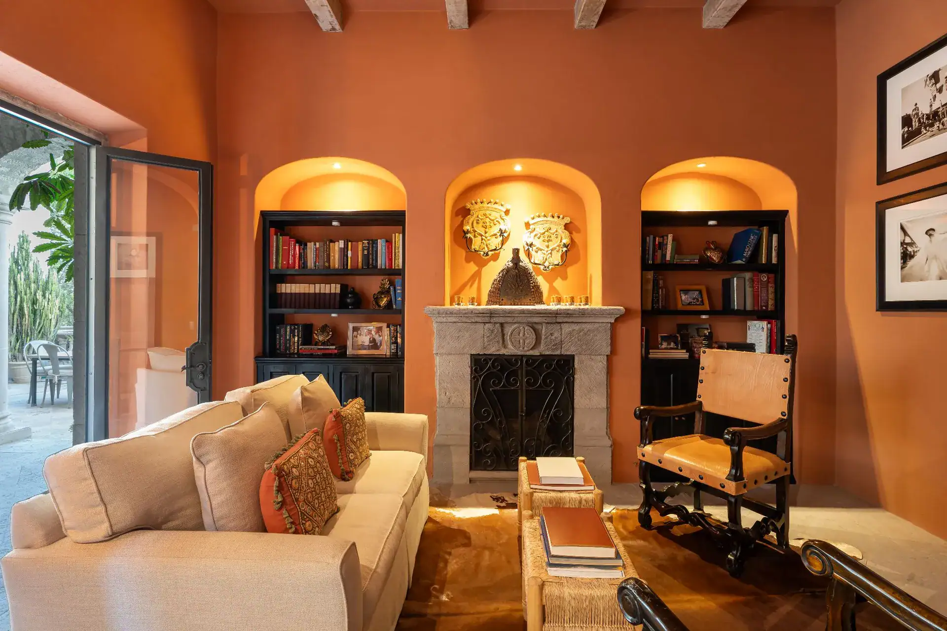Casa Dos Casas, library sitting room with terracotta walls, lit arched niches with bookshelves and a cream sofa, San Miguel de Allende