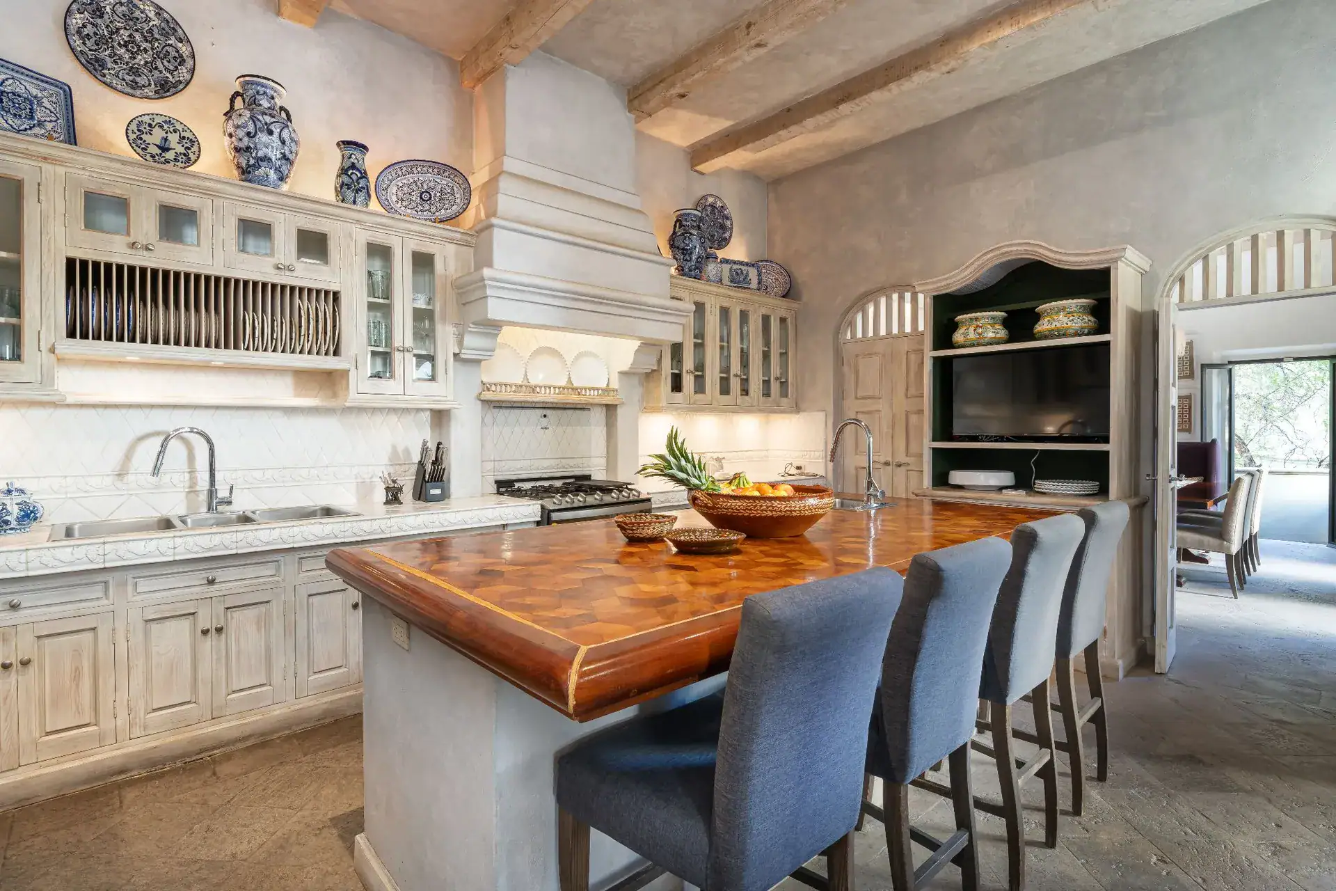 Casa Dos Casas, kitchen with a wood-topped island, blue upholstered stools, a plate rack and blue-and-white china, San Miguel de Allende