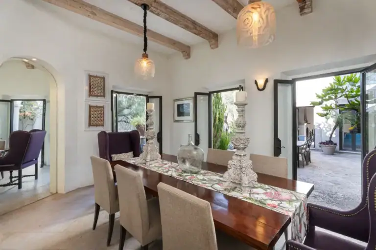 Casa Dos Casas, dining room with a long wood table, upholstered chairs and doors opening to the courtyard, San Miguel de Allende