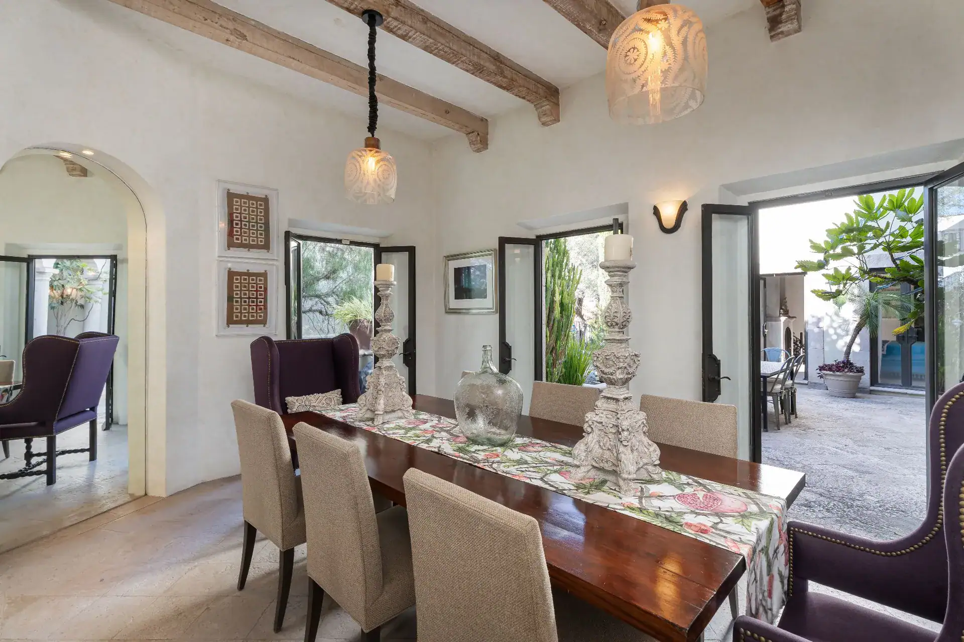 Casa Dos Casas, dining room with a long wood table, upholstered chairs and doors opening to the courtyard, San Miguel de Allende
