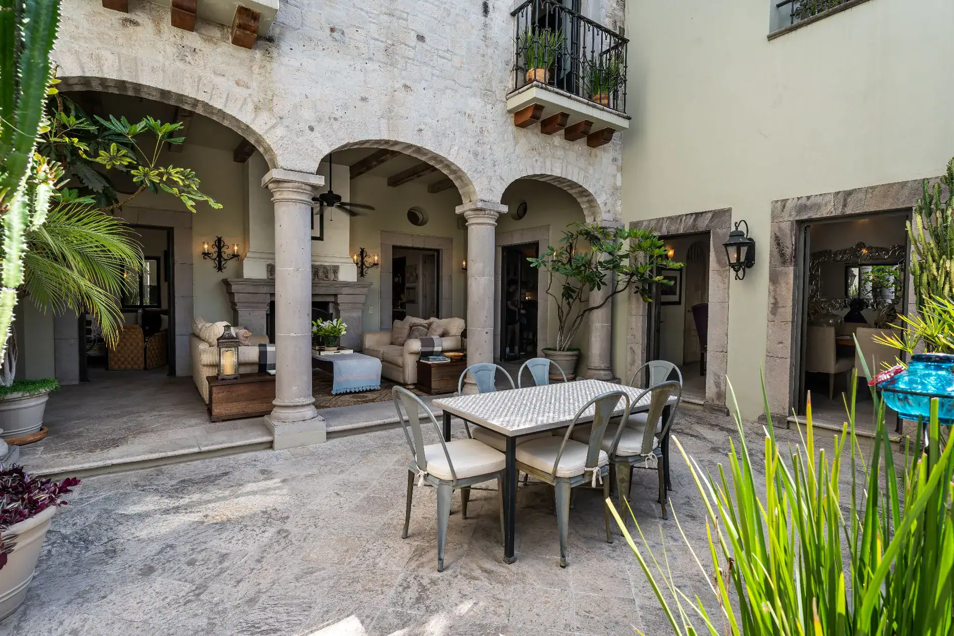 Casa Dos Casas, stone arcade and courtyard dining table beside an outdoor seating area with potted plants, San Miguel de Allende