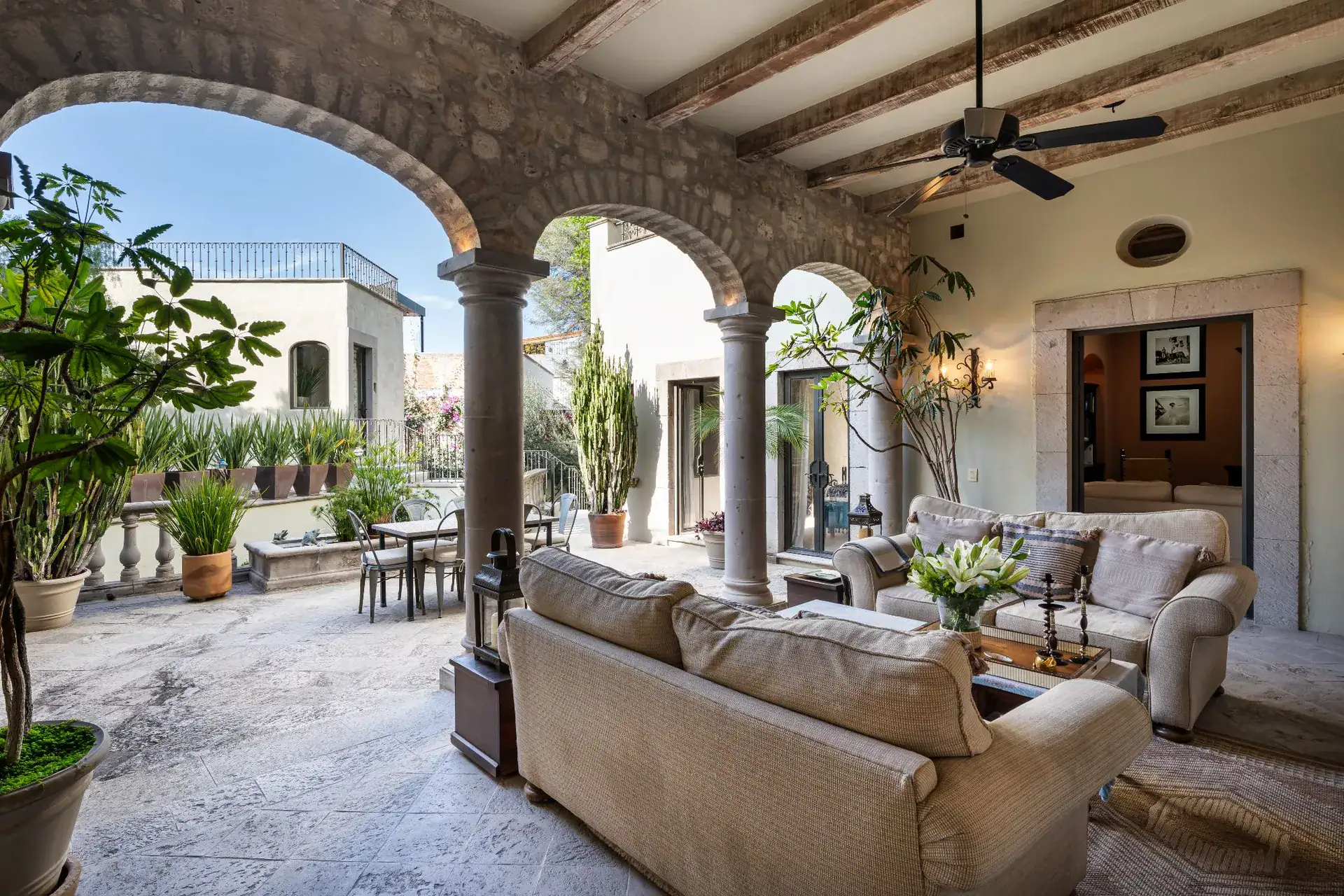 Casa Dos Casas, covered arcade lounge with sofas and a ceiling fan opening onto the courtyard dining area, San Miguel de Allende