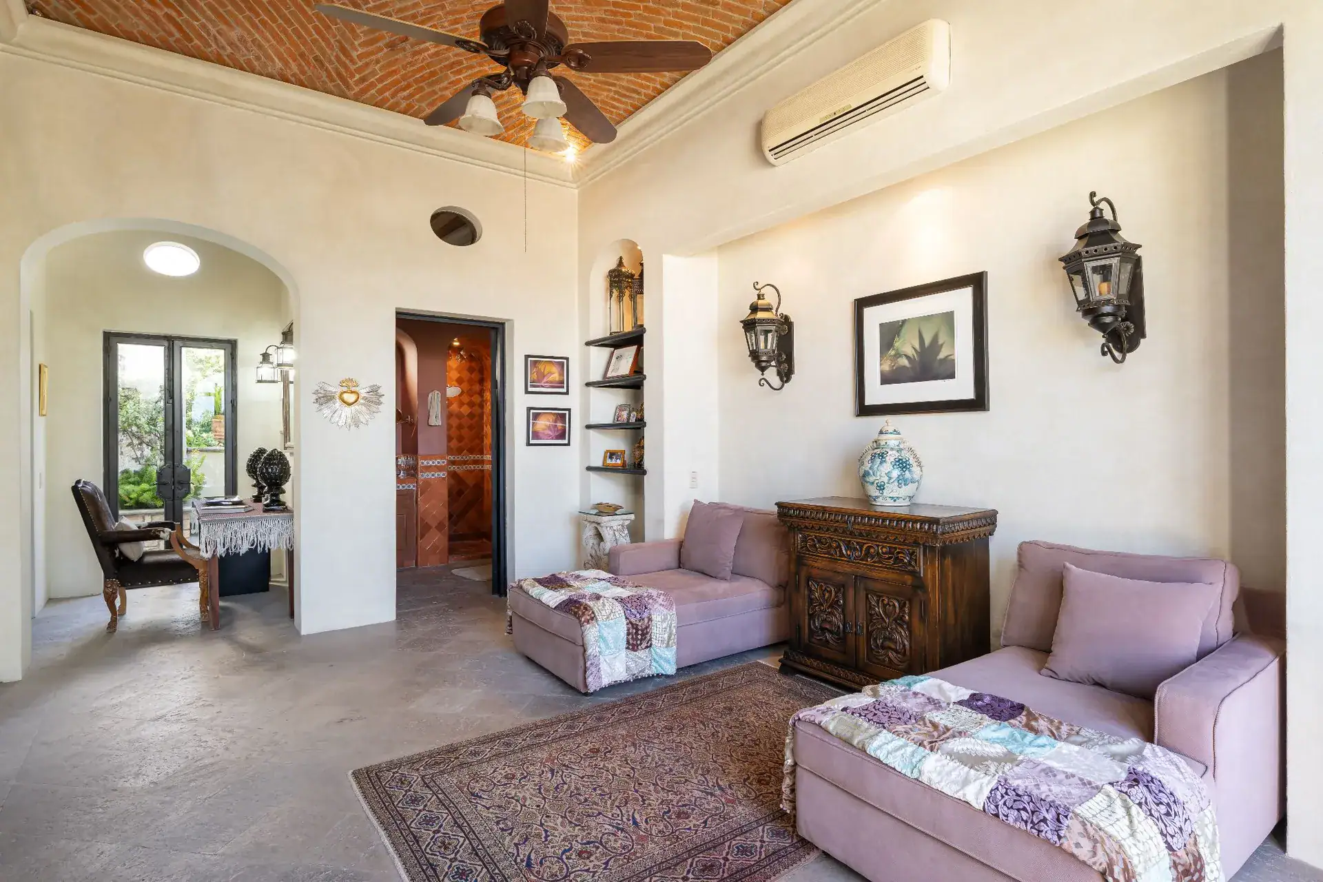 Casa Dos Casas, bedroom sitting area with pink sofas, a carved chest and an arched doorway, San Miguel de Allende