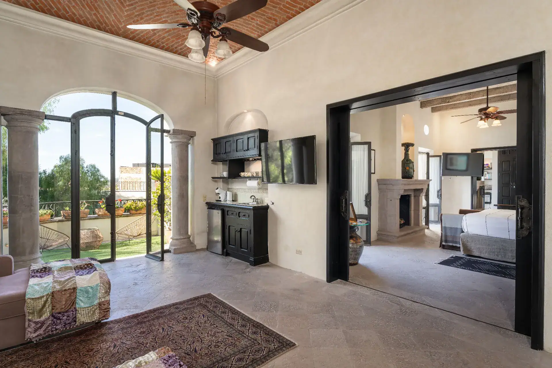 Casa Dos Casas, bedroom suite with an arched glass door to a balcony and a view of the bed through black-framed doors, San Miguel de Allende