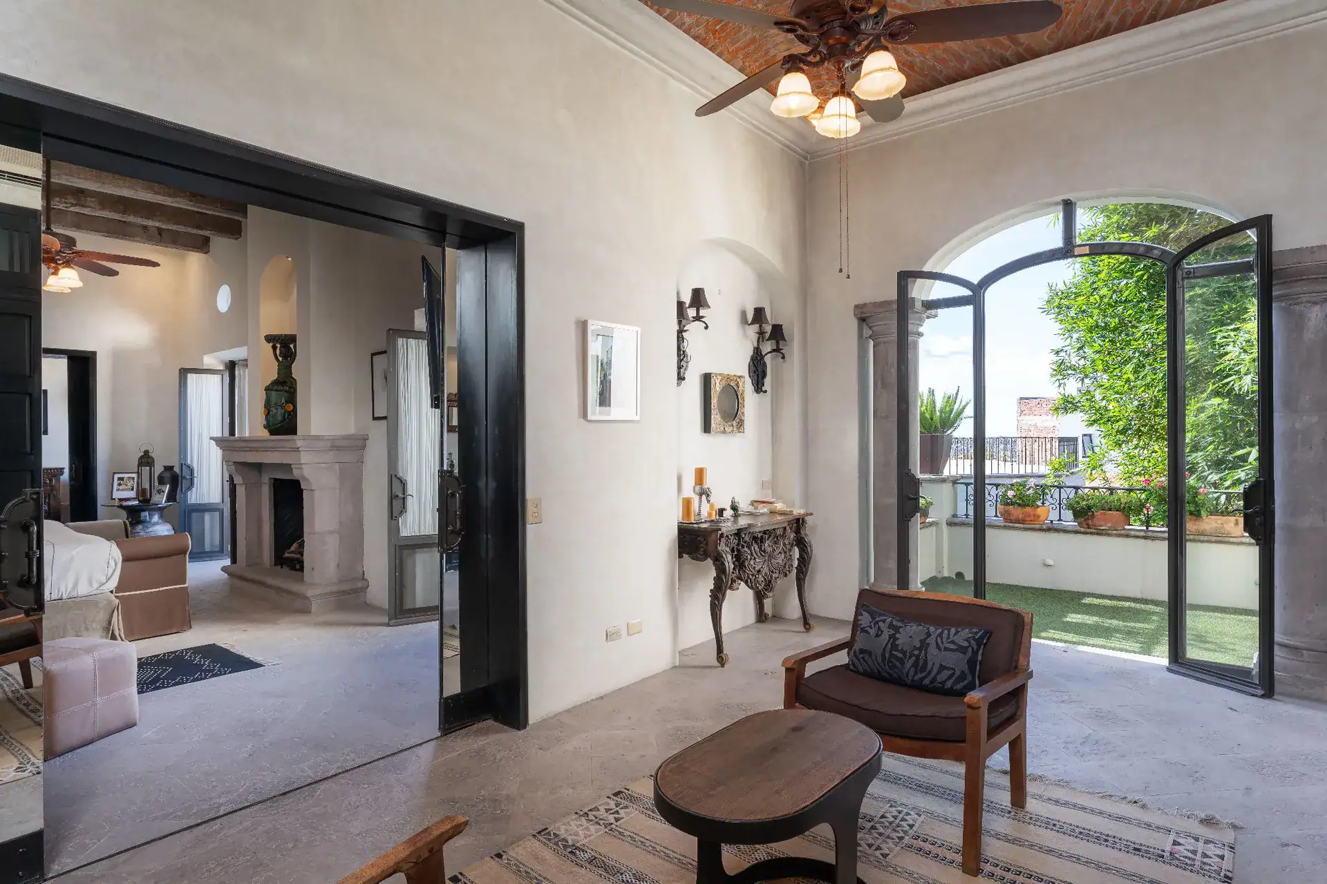 Casa Dos Casas, sitting area with an oval coffee table, armchair and arched doors to a balcony, San Miguel de Allende