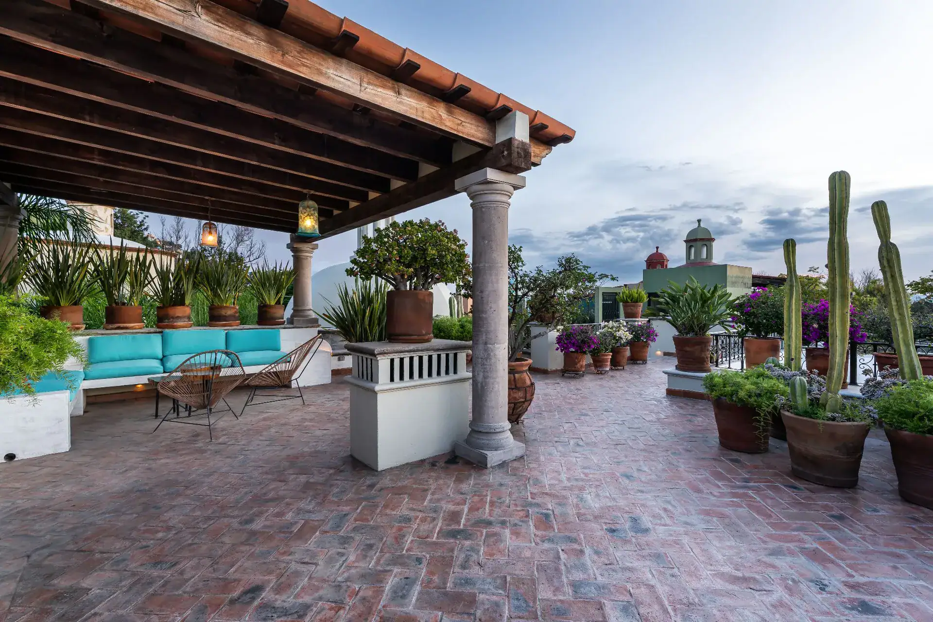 Casa Dos Casas, rooftop terrace with a tiled pergola, potted cacti and a brick floor overlooking town, San Miguel de Allende