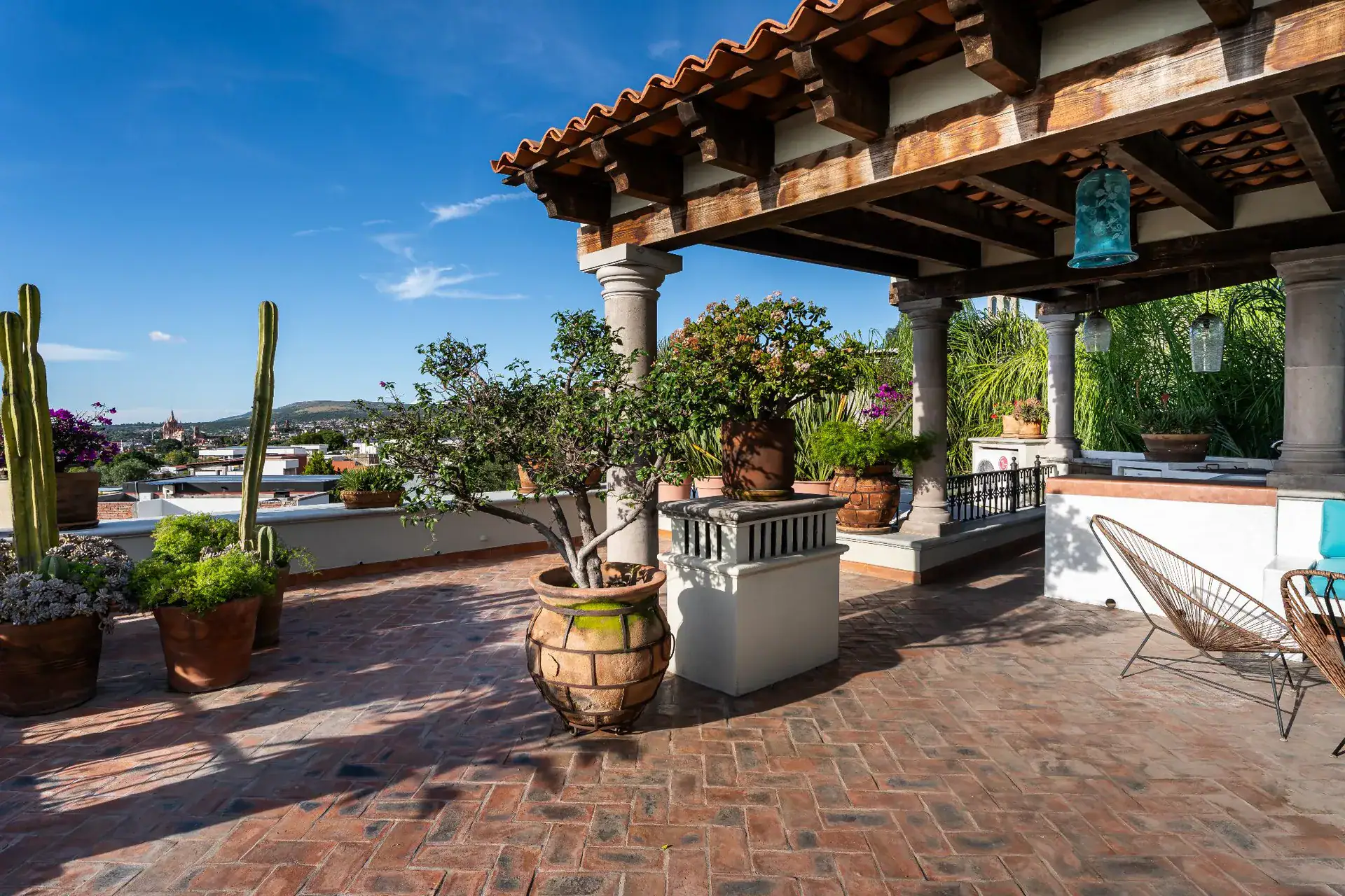 Casa Dos Casas, rooftop terrace with potted plants and cacti beneath a tiled pergola, San Miguel de Allende