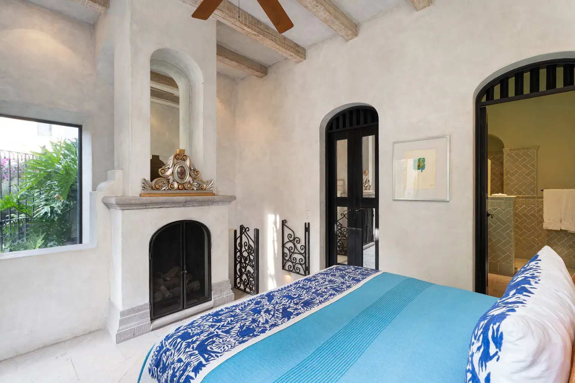 Casa Dos Casas, bedroom with a fireplace, blue bedspread and arched doorways, San Miguel de Allende