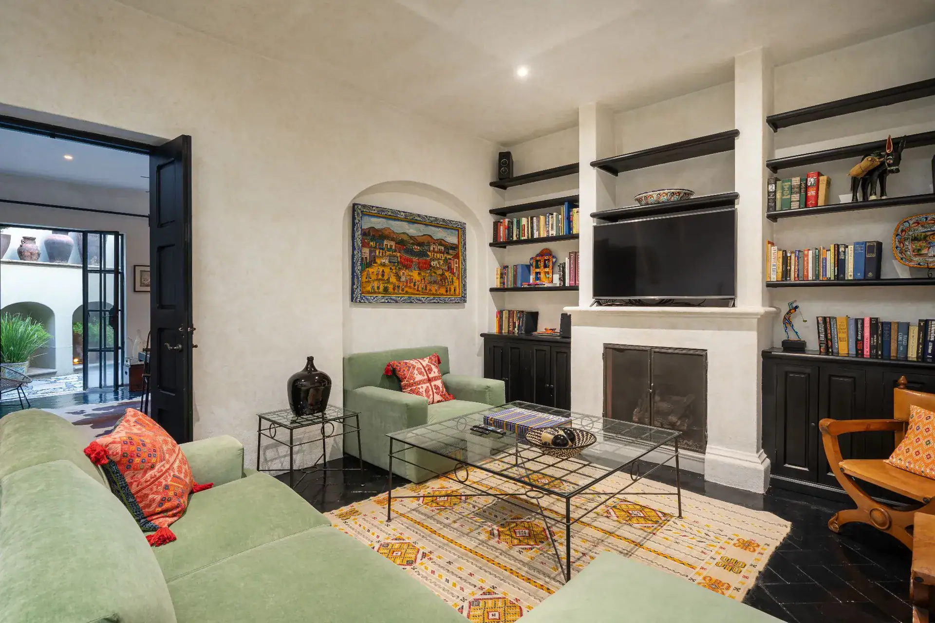 Casa Dos Casas, family room with green sofas, built-in bookshelves, a fireplace and a television, San Miguel de Allende