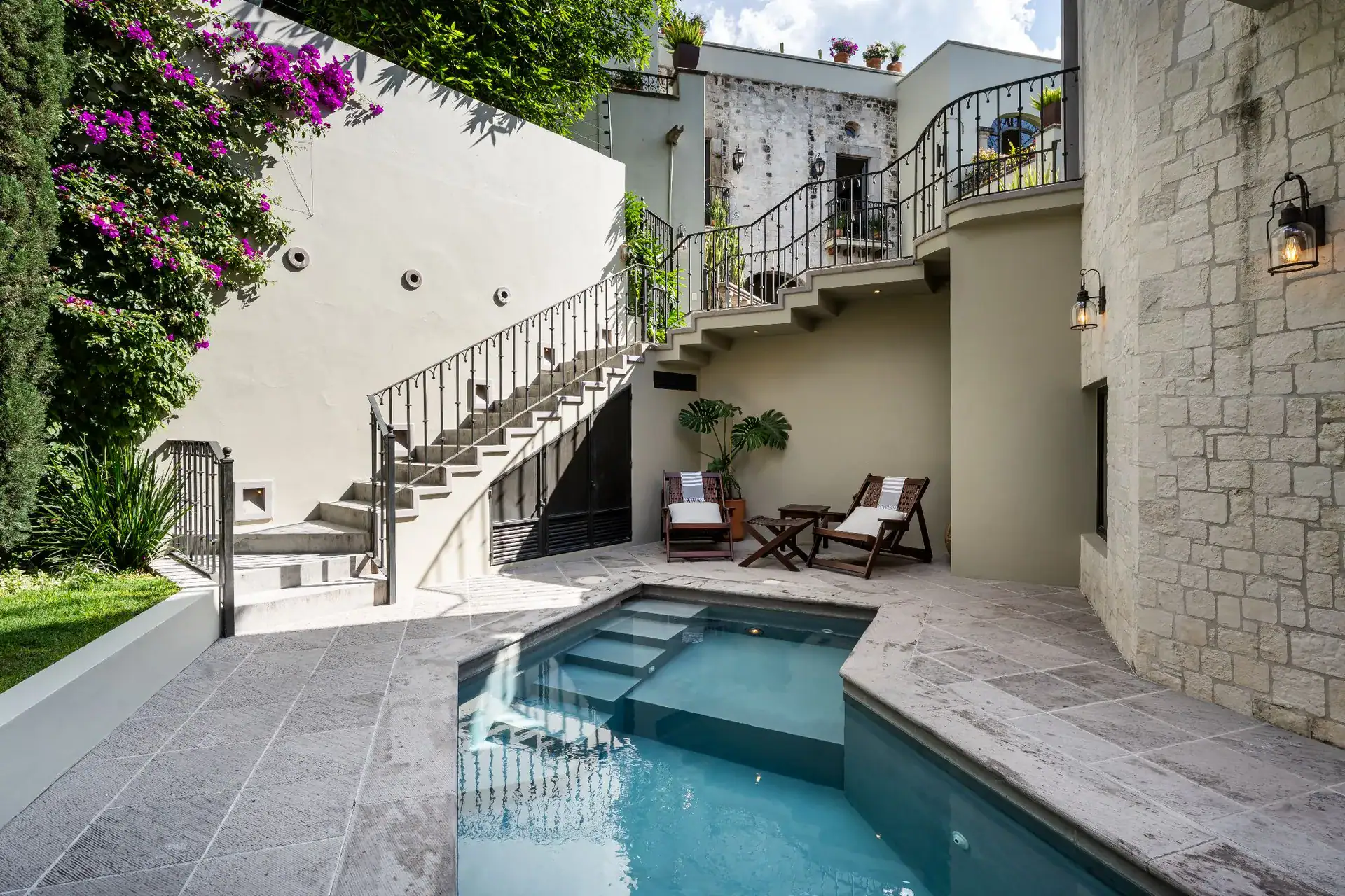 Casa Dos Casas, courtyard pool with stone terraces, a curved staircase and lounge chairs under bougainvillea, San Miguel de Allende