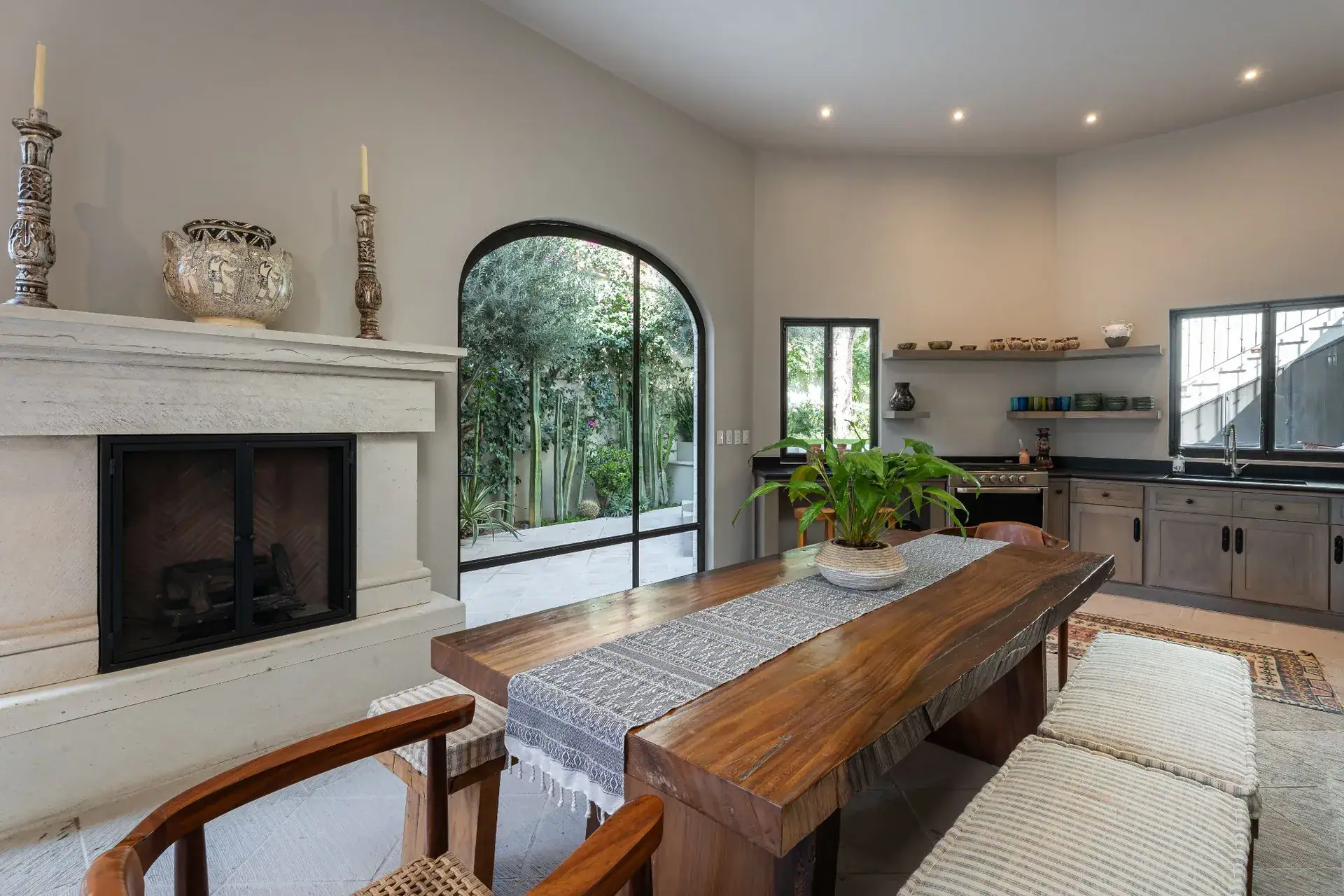 Casa Dos Casas, casita dining area with a long wood table, fireplace and kitchen, San Miguel de Allende