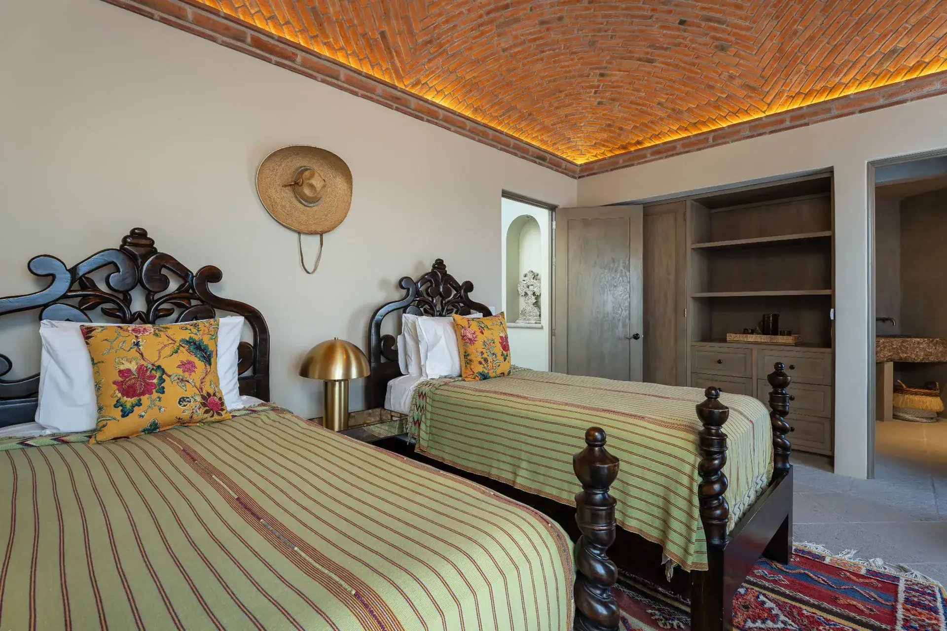 Casa Dos Casas, bedroom with twin carved dark wood beds, striped bedding and a brick vaulted ceiling, San Miguel de Allende