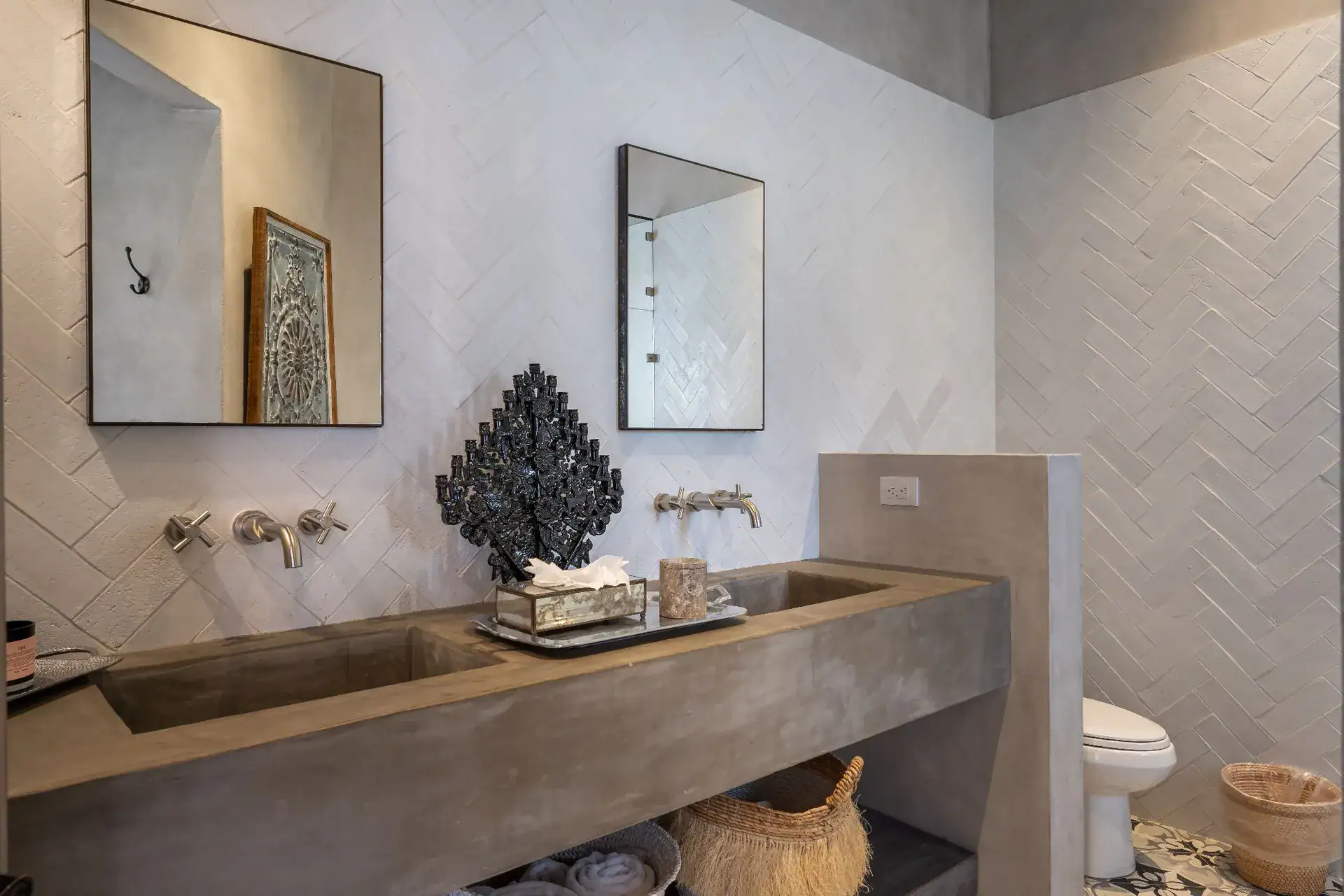 Casa Dos Casas, bathroom with a poured concrete double sink, wall-mounted faucets and white herringbone tile, San Miguel de Allende