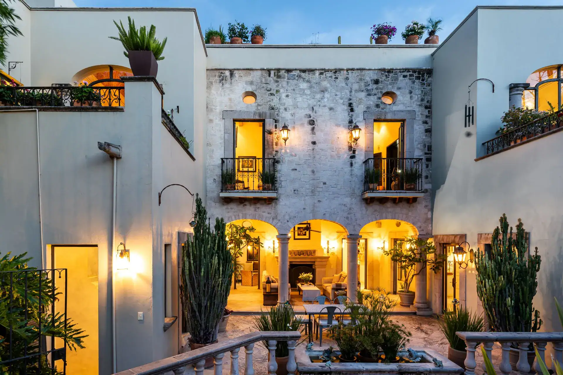 Casa Dos Casas, illuminated arcaded courtyard of the house at dusk with glowing windows, San Miguel de Allende