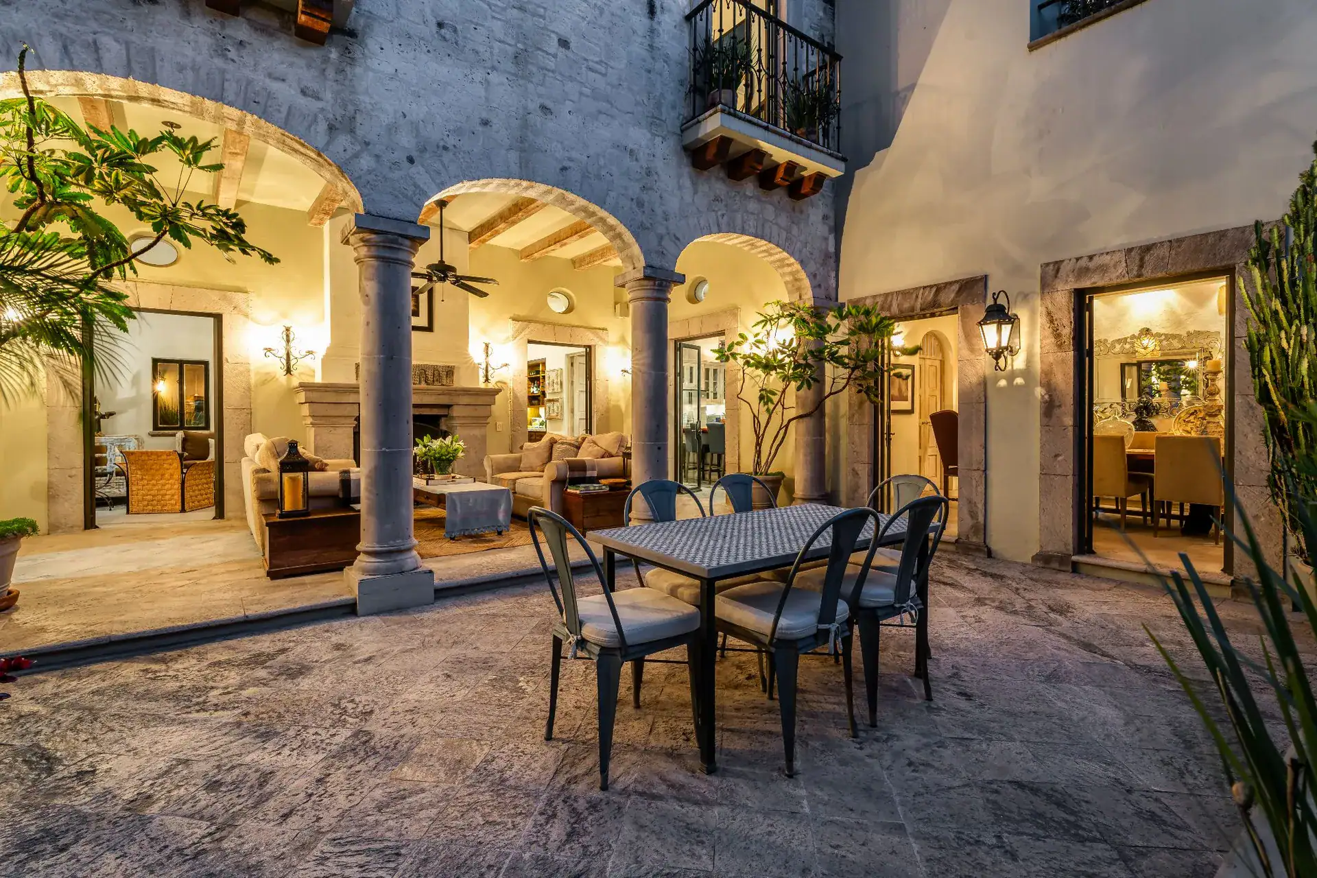 Casa Dos Casas, courtyard loggia lit at night with an outdoor dining table and arched seating area, San Miguel de Allende