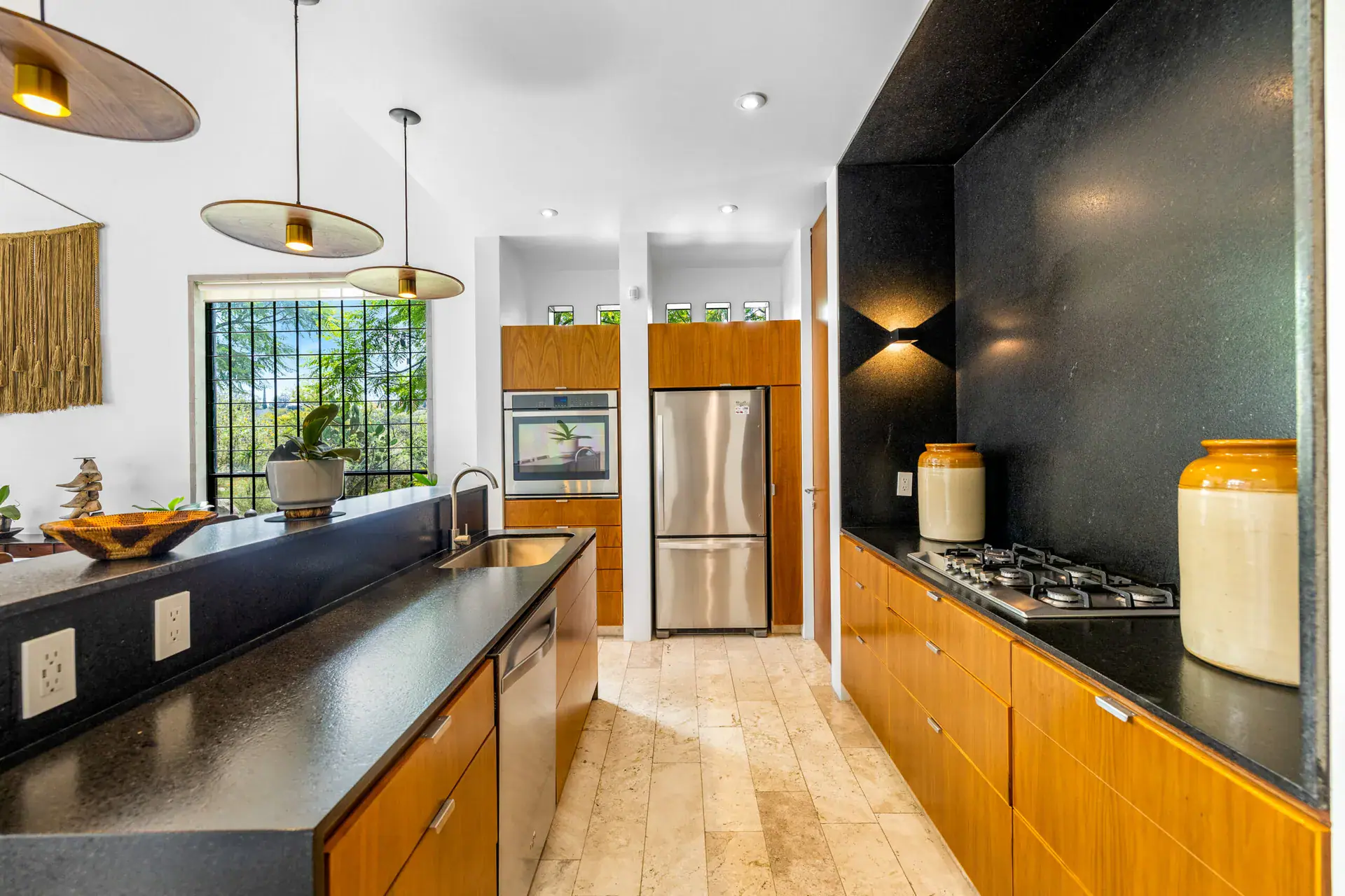 Casa Dos Gatos, kitchen with a black backsplash, a gas cooktop, wood cabinets and a stainless refrigerator, San Miguel de Allende