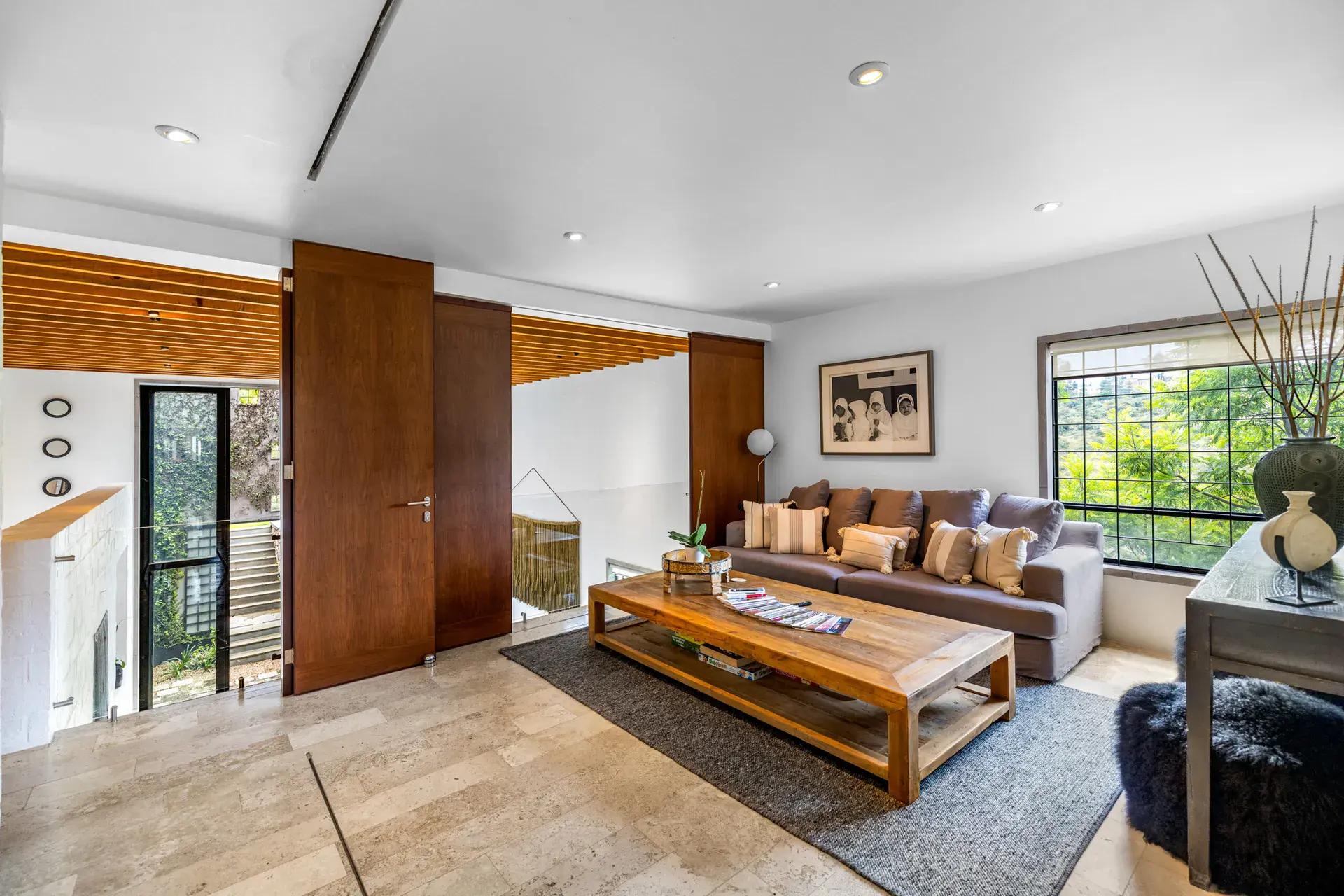 Casa Dos Gatos, upper sitting room opening to the double-height space with a wood-slat ceiling, San Miguel de Allende