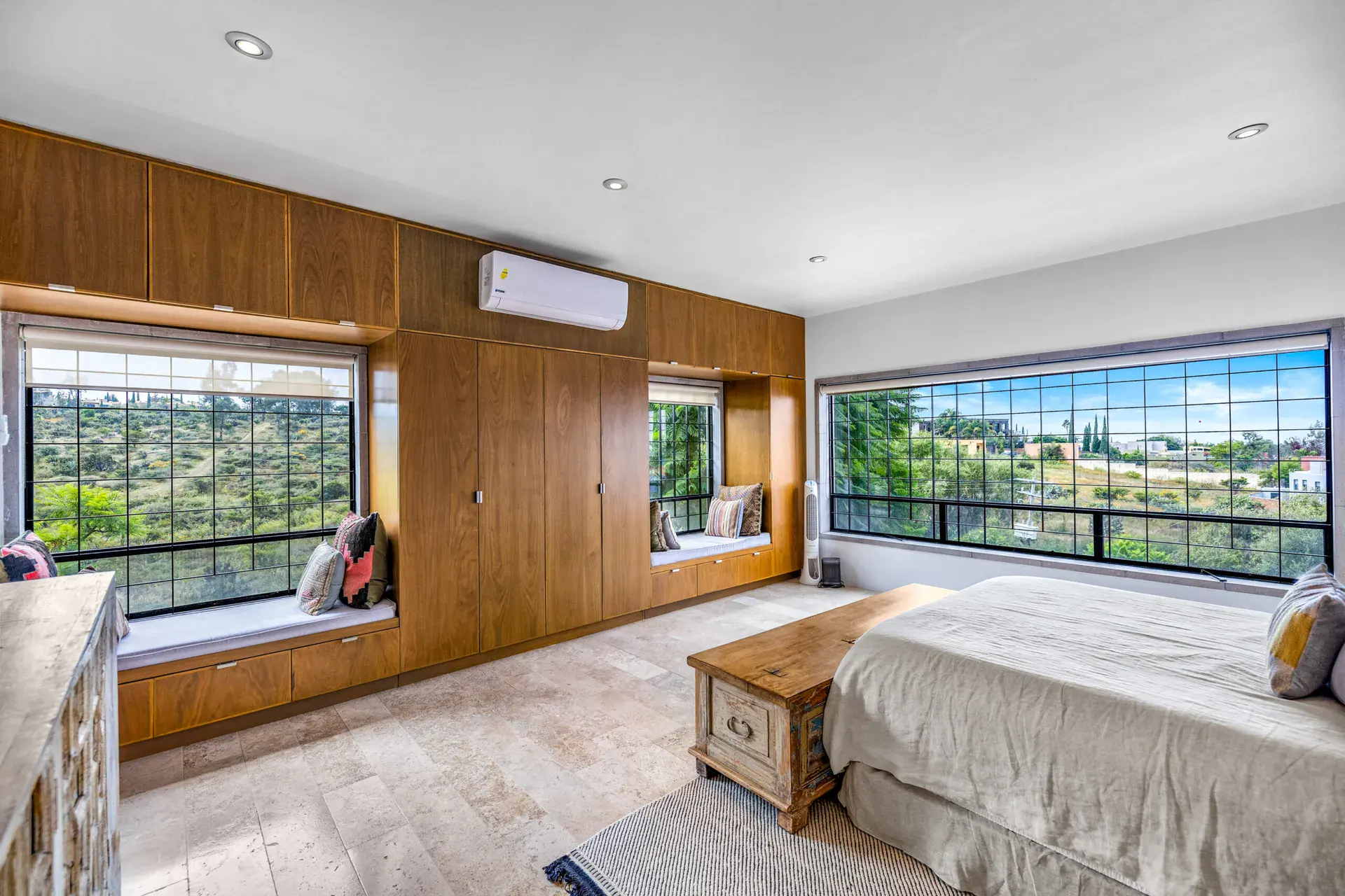 Casa Dos Gatos, bedroom with wood built-in wardrobes, a window seat and a wide landscape window, San Miguel de Allende