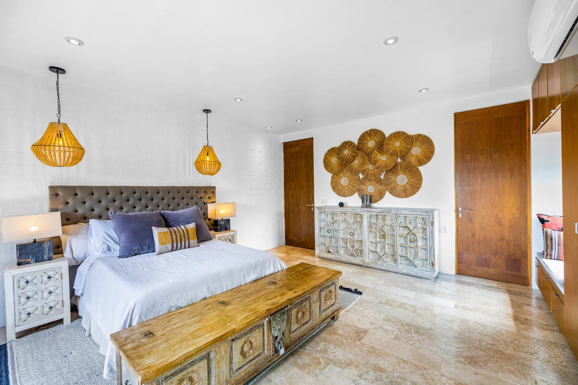 Casa Dos Gatos, bedroom with a tufted headboard, woven pendant lights and a carved wood chest at the foot of the bed, San Miguel de Allende