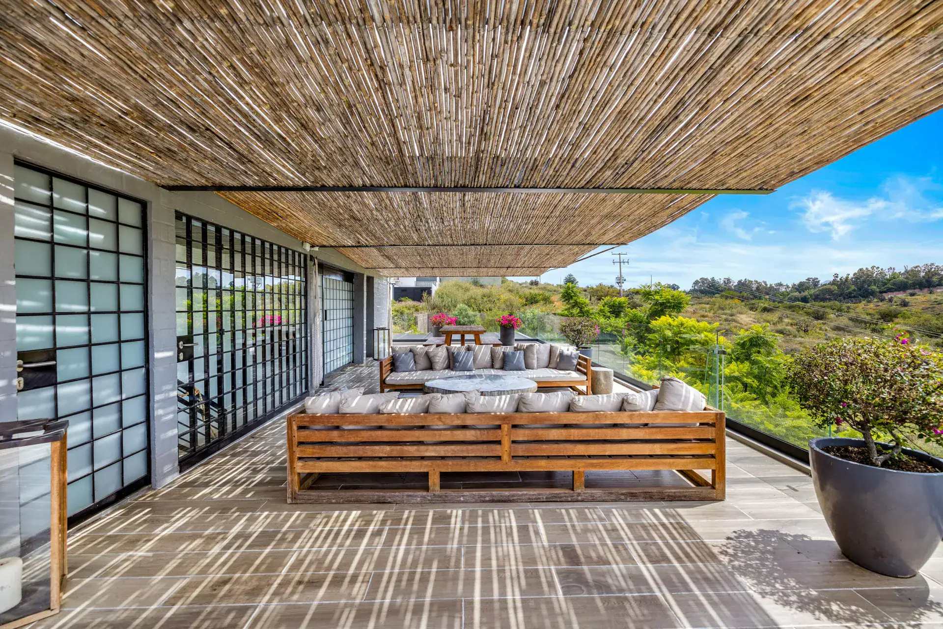 Casa Dos Gatos, covered terrace with a bamboo ceiling, teak sofas and glass railing over the hills, San Miguel de Allende