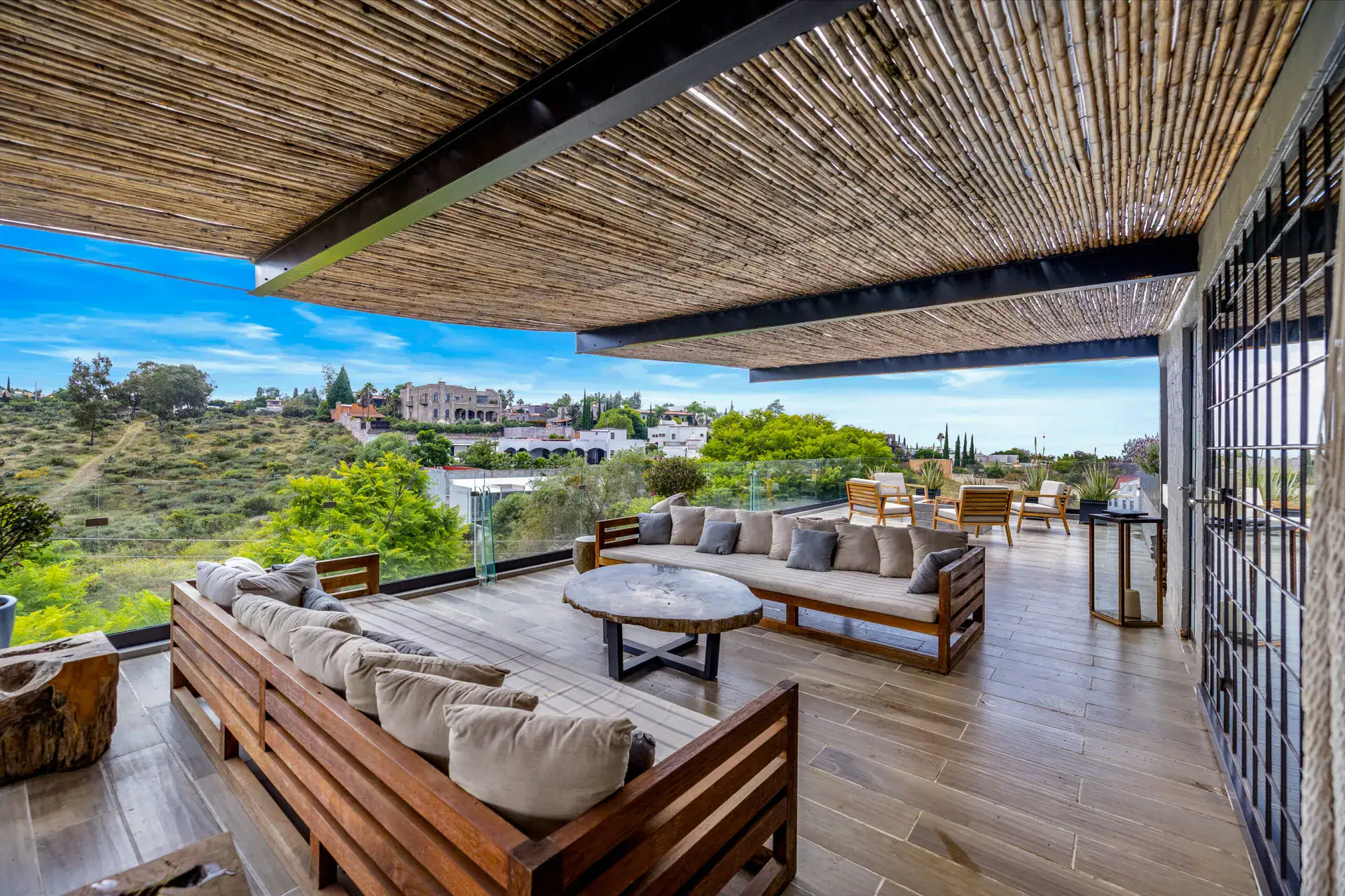 Casa Dos Gatos, terrace seating with a teak sofa, a round table and a view of the landscape, San Miguel de Allende