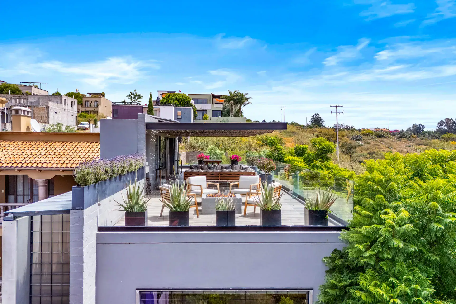 Casa Dos Gatos, aerial view of the house's rooftop terrace with a dining set and planters over the landscape, San Miguel de Allende