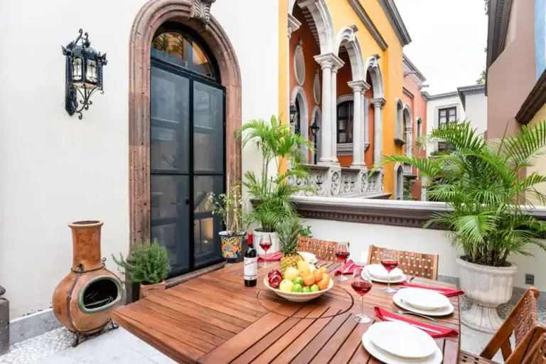 Casa Elegante, wood balcony dining table with plants and a view of colorful facades, San Miguel de Allende