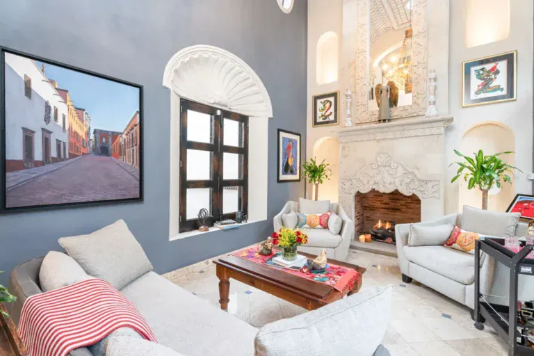 Casa Elegante, living room with a gray accent wall, a white fireplace and cream armchairs, San Miguel de Allende