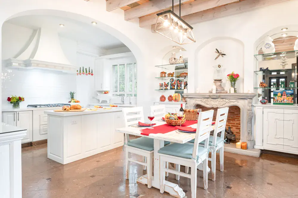 Casa Elegante, kitchen with white cabinets, an island and a stone fireplace, San Miguel de Allende
