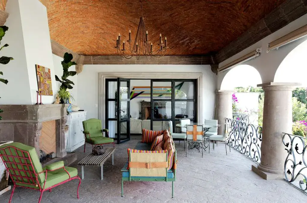 Casa Eloísa, covered terrace with a brick vaulted ceiling, a stone fireplace and colorful chairs, San Miguel de Allende