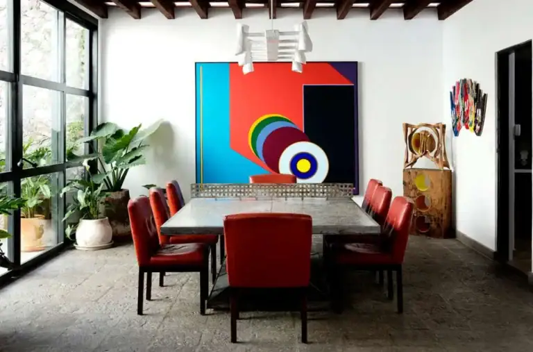 Casa Eloísa, dining room with steel windows, red chairs and a large abstract painting, San Miguel de Allende