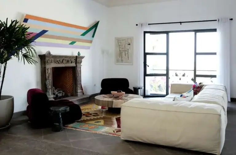 Casa Eloísa, living room with a stone fireplace, a cream sofa and a kilim rug, San Miguel de Allende