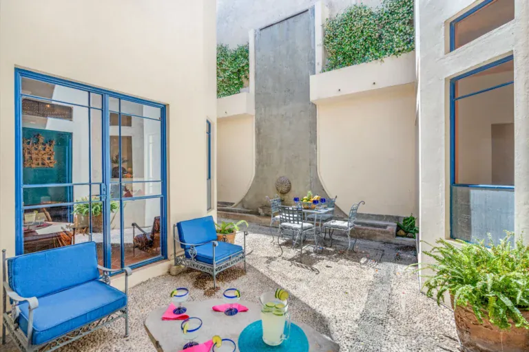 Casa Fallingwater, courtyard with blue armchairs, a bistro table and a stone water wall, San Miguel de Allende