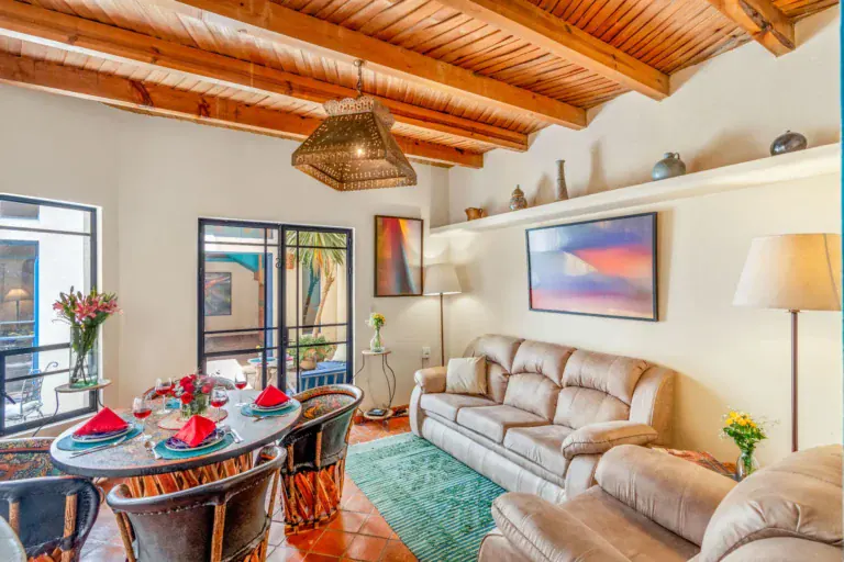 Casa Fallingwater, living room with a beamed ceiling, a dining table and tan sofas, San Miguel de Allende