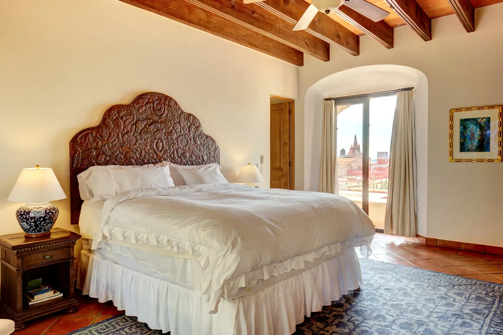 Casa Familia, primary bedroom with a carved headboard and a terrace view, San Miguel de Allende