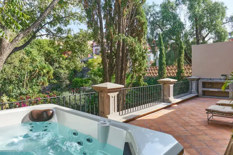 Casa Familia, terrace hot tub beside a lounge chair with trees behind, San Miguel de Allende