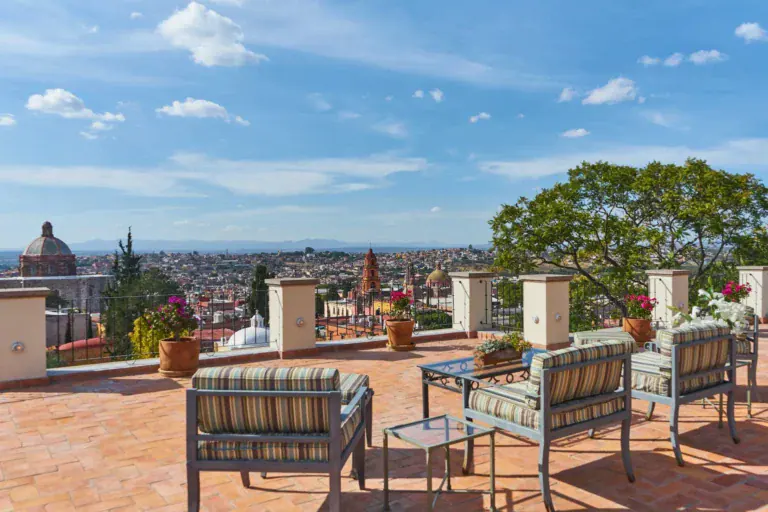 Casa Familia, rooftop terrace with striped chairs and a view over the Parroquia and the city, San Miguel de Allende