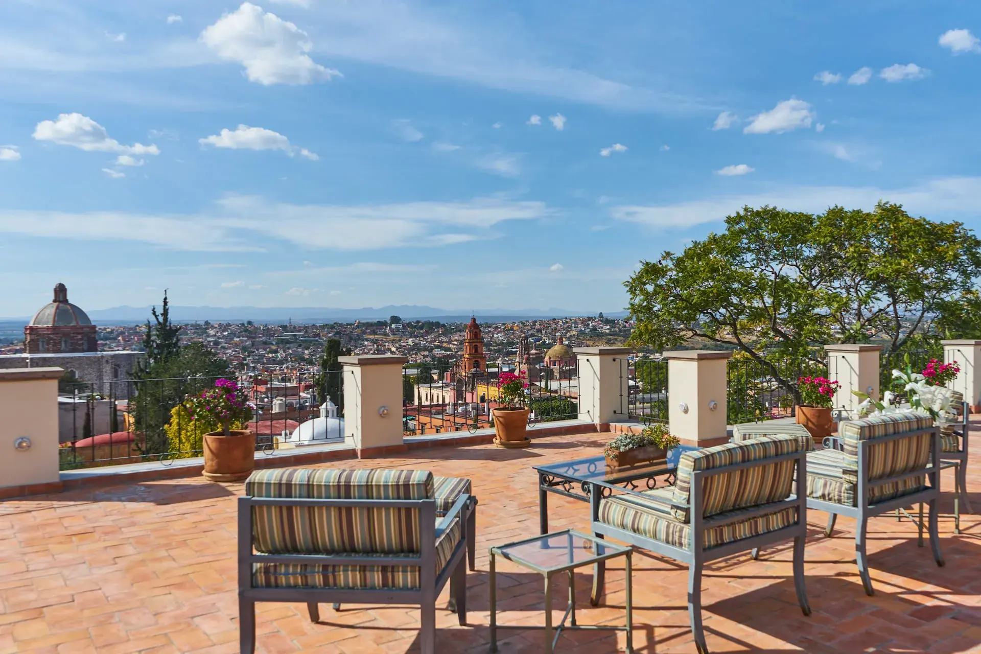 Casa Familia, rooftop terrace with striped chairs and a view over the Parroquia and the city, San Miguel de Allende