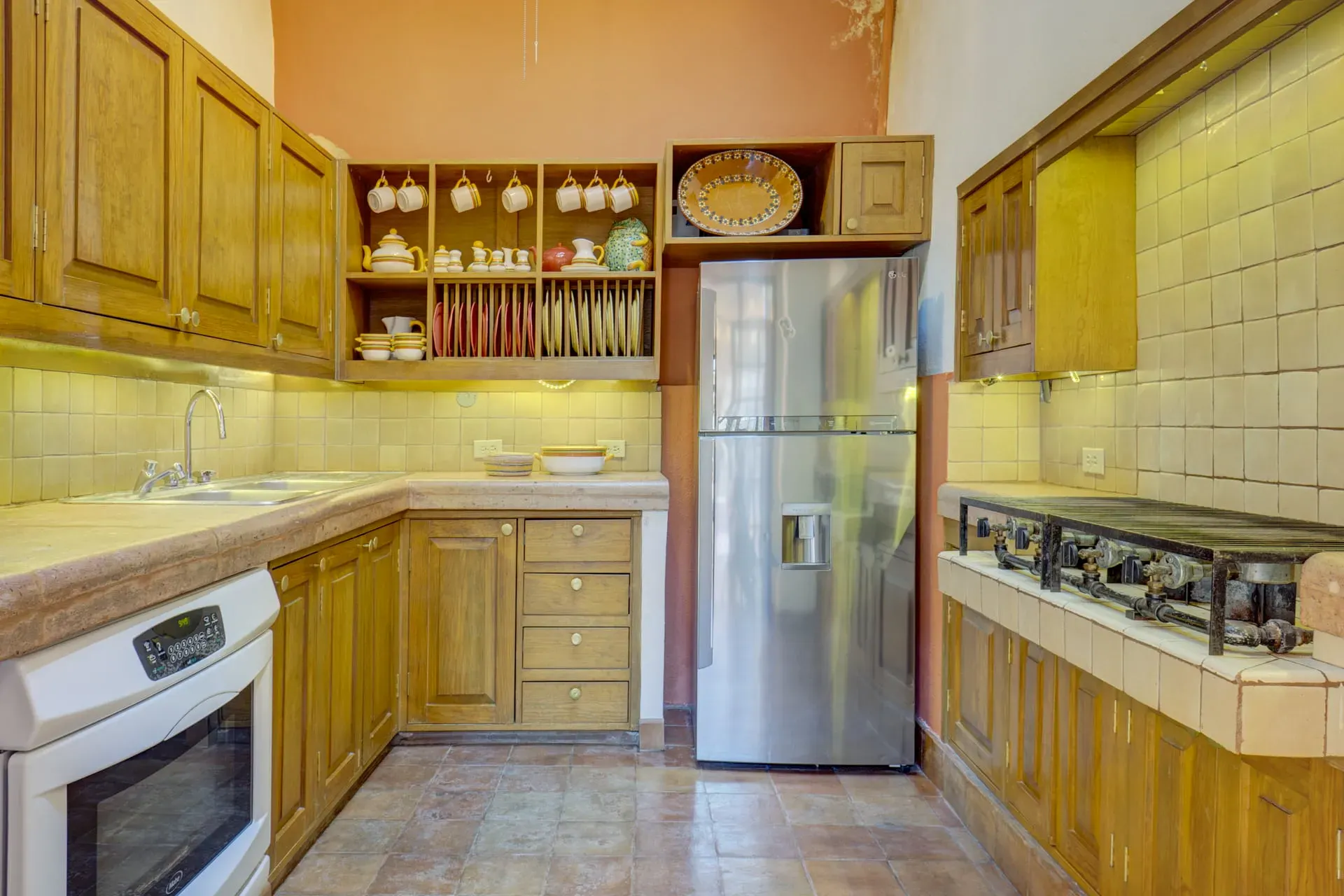 Casa Firenze, kitchen with wood cabinets, tile counters, a stainless refrigerator, a white oven and a gas cooktop, San Miguel de Allende